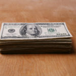 Photo of a stack of dollar bills on a wooden surface