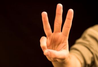 Photo of a hand holding up three fingers.