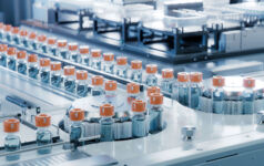 Vaccine Production Facility. Medication Manufacturing Process. Glass Vials with Orange Caps on Conveyor Belt. Medical Ampoule Production Line at Modern Pharmaceutical Factory.
