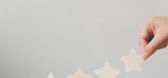 Hand putting wooden five star shape on table. The best excellent business services rating customer experience concept.